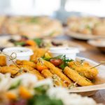 An assortment of tasty appetizers including schnitzel, served on eco-friendly bamboo plates at a festive gathering.